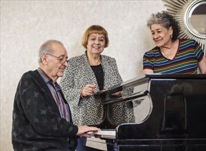 Senior women listening to man playing piano