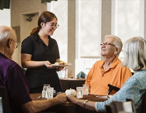 Waitress bringing meal to senior people at table