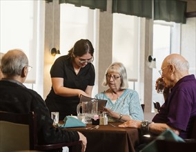 Waitress explaining menu to senior woman at table