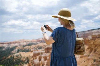 USA, Utah, Bryce Canyon, Woman photographing canyon with smart phone