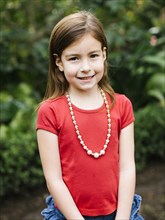 USA, California, Orange County, Portrait of smiling girl (6-7) wearing bead necklace