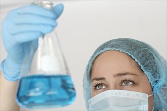 Laboratory technician in face mask holding flask with liquid