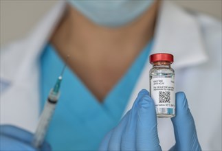 Close-up of doctors hands holding Covid-19 vaccine and syringe