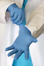 Person putting on blue surgical gloves