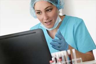 Woman in protective lab workwear sitting in front of laptop