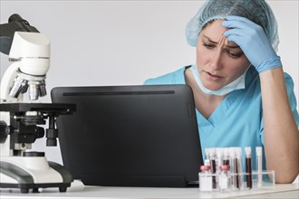 Woman in protective lab workwear sitting in front of laptop