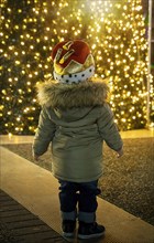 Boy in Christmas hat watching illuminated Christmas tree