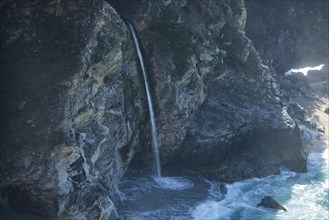 USA, California, Big Sur, Waterfall falling from cliff at sea side