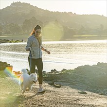 USA, California, San Francisco, Woman with Samoyed puppy running on beach