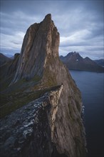 Norway, Senja, Man sitting on cliff edge near Segla mountain