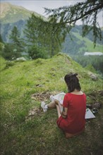Switzerland, Obergoms, Young woman painting with watercolor in Swiss Alps