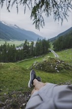 Switzerland, Obergoms, Legs of man relaxing on grass in Swiss Alps