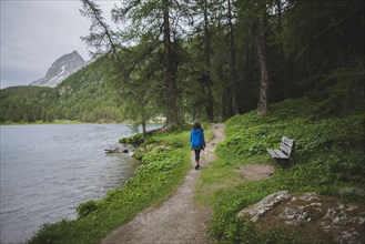Switzerland, Bravuogn, Palpuognasee, Young woman walking by Palpuognasee lake in Swiss Alps