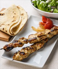 Plate of grilled chicken with pita bread and salad
