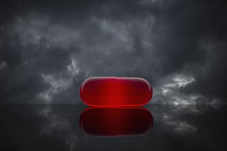 Red pill on cloudy background