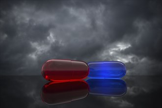 Red and blue pills on cloudy background
