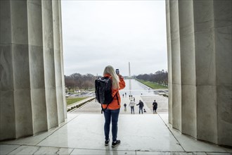 USA, Washington, Tourist takes photo of Washington Monument across pond at National Mall using smartphone