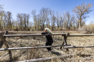 USA, Idaho, Bellevue, Senior woman relaxing on rustic rail fence