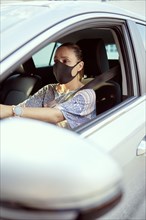 Woman with face mask driving car