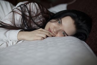 Portrait of young woman lying on bed