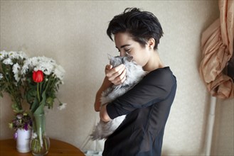 Woman cuddling cat at home