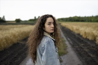Russia, Omsk, Portrait of young woman with brown hair standing in field