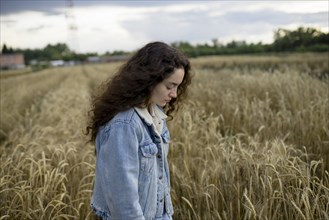 Russia, Omsk, Young woman standing in wheat field