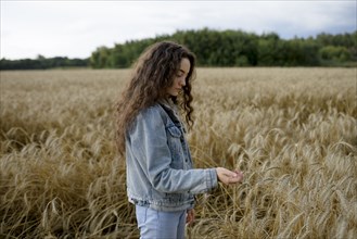 Russia, Omsk, Young woman standing in wheat field