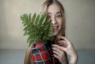 Portrait of young woman with fern leaf