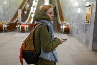 Russia, Novosibirsk, Young woman standing by escalator in subway