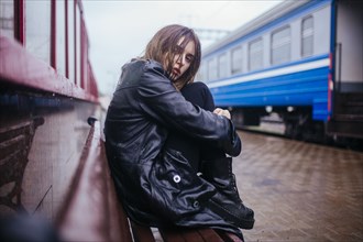 Belarus, Minsk, Young woman waiting on train platform in rain