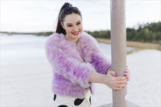 Belarus, Minsk, Portrait of young woman in pink cur coat on beach