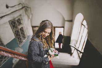 Bride standing on stairs while groom is waiting at entrance