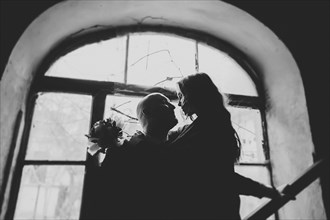 Newlywed couple embracing in window