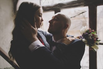 Newlywed couple embracing in window