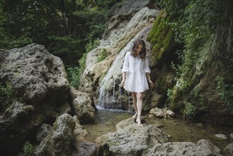 Ukraine, Crimea, Young woman walking barefoot on rocks near waterfall