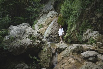 Ukraine, Crimea, Young woman walking barefoot on rocks in canyon