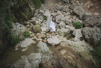 Ukraine, Crimea, Young woman standing on rock in river