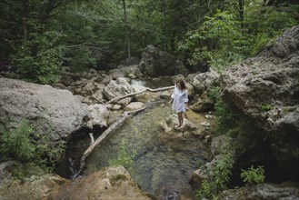 Ukraine, Crimea, Young woman standing on rock in river