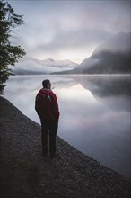 Austria, Plansee, Young man standing by Plansee lake at sunrise