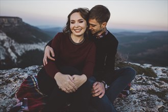 Ukraine, Crimea, Young couple sitting and hugging near canyon