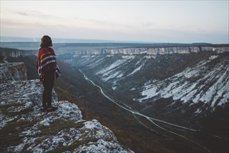 Ukraine, Crimea, Young woman covered with plaid looking at canyon