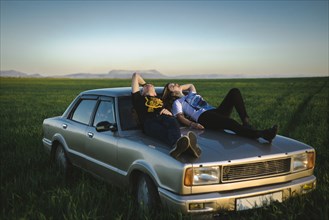 Ukraine, Crimea, Couple sitting on old fashioned car in rural scenery