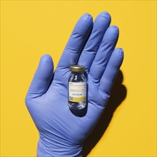Studio shot of vial with Covid-19 vaccine on hand in blue latex glove