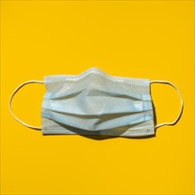 Surgical mask on yellow background