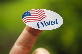 Close-up of I voted sticker on finger