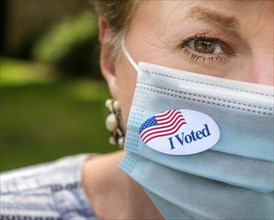 Close-up of woman in surgical mask and of I voted sticker