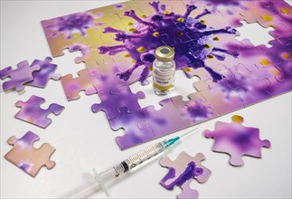 Studio shot of puzzle with Coronavirus model and vaccine vials and syringe