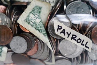 Close-up of coins and banknotes in jar labeled Payroll