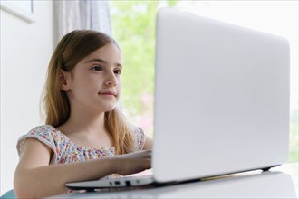 Girl (6-7) using laptop at home